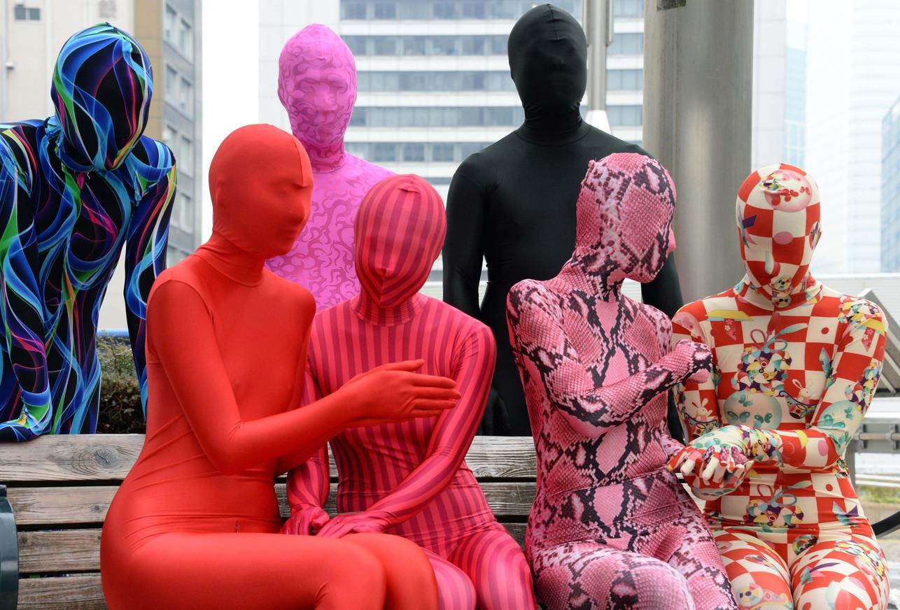 TO GO WITH STORY Japan-culture-costumes,FEATURE by Harumi Ozawa This picture taken on January 25, 2014 shows members of Tokyo Zentai Club chating each other at a park in Tokyo. Some meet through Internet forums and through gatherings like the Tokyo Zentai Club, whose ten members get together every other month, just like any other group, to hold barbecues or parties. Unlike any other group, they are covered head-to-toe in skintight Lycra.They are part of a small subset in Japan with a fetish for wearing outfits called "zentai" -- an abbreviation of "zenshintaitsu", which means "full body suit" -- who say they are seeking liberation through the complete sublimation of the physical self. AFP PHOTO / Yoshikazu TSUNO